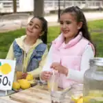 25 Unique Fundraising Ideas for Teens That Are Easy to Organize Girls enjoying lemonade stand at a fundraising event.