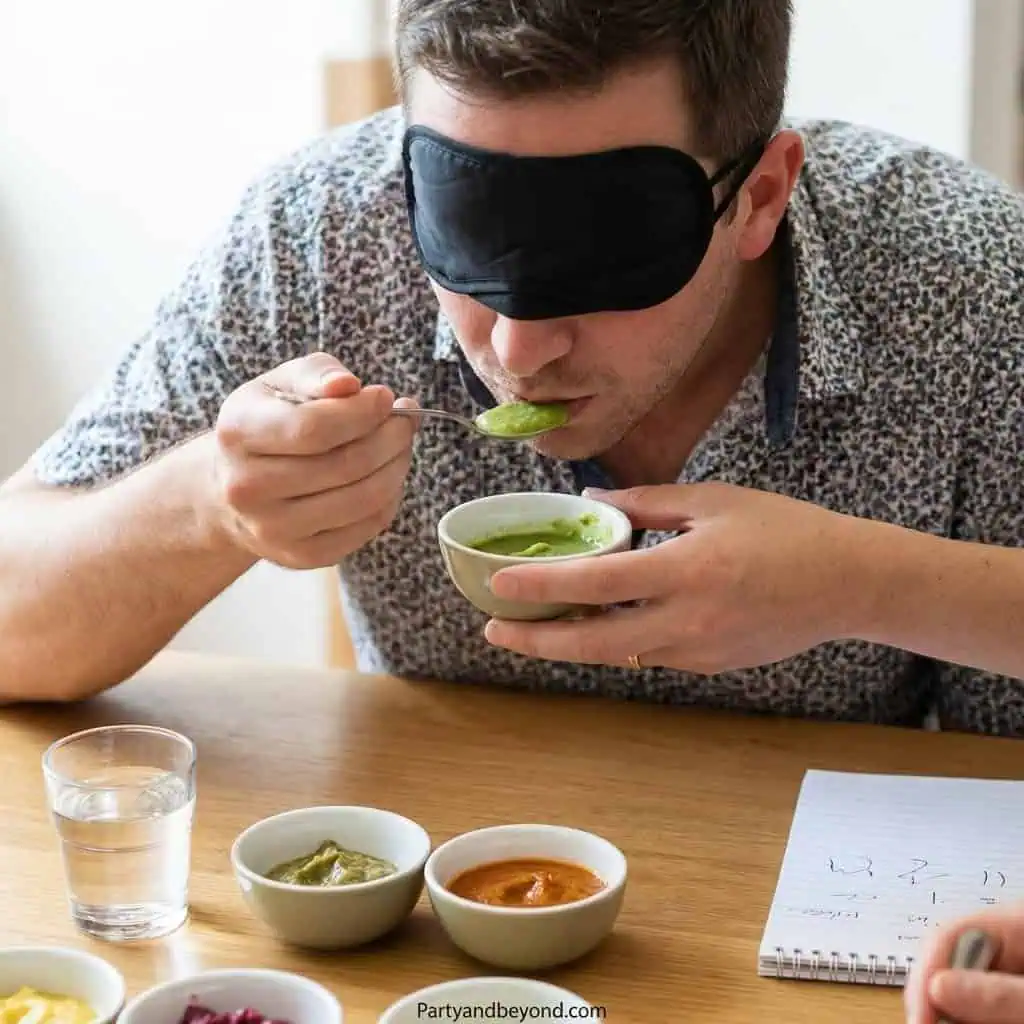 Person tasting spicy food with a blindfold during a fun game.