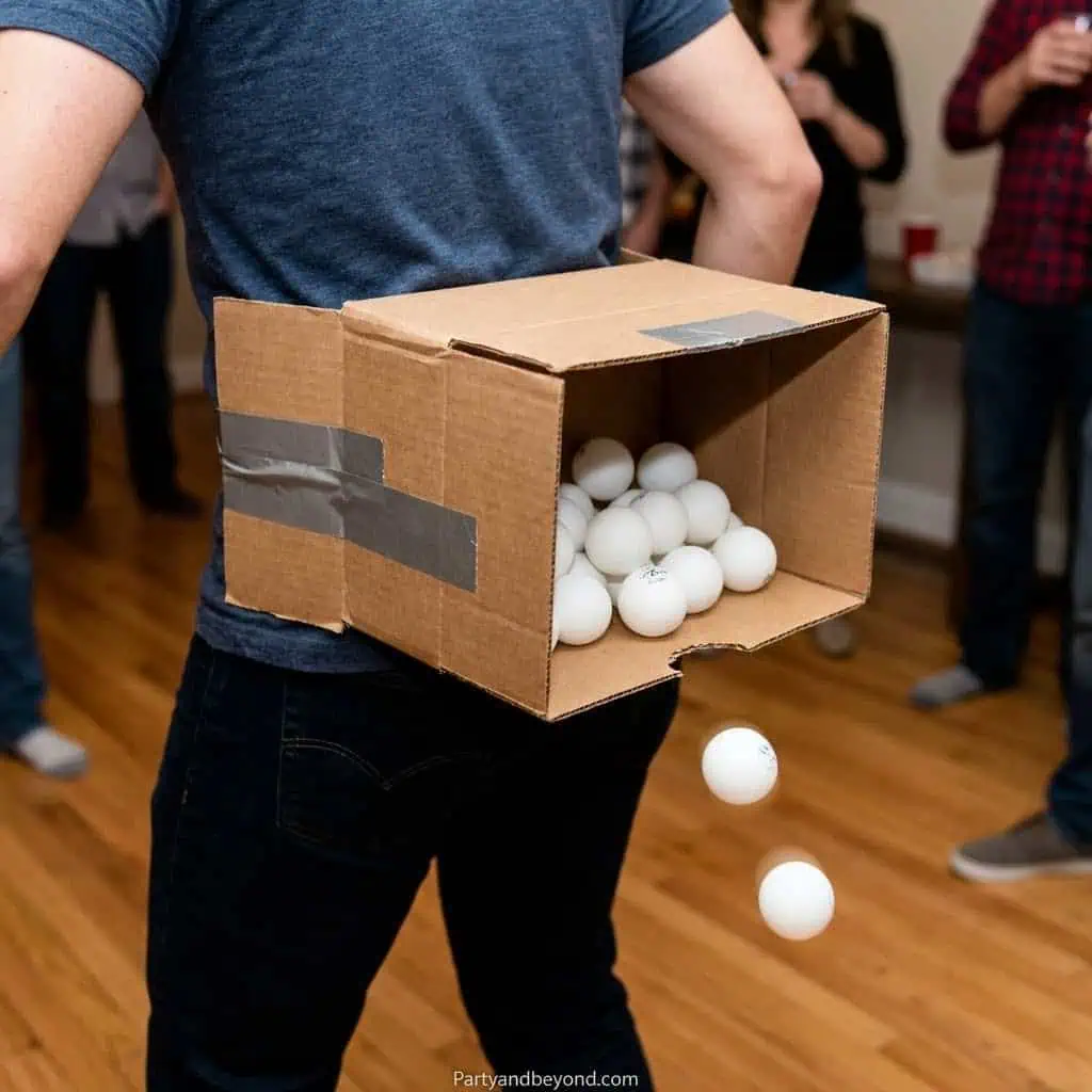 Person holding a cardboard box with ping pong balls at a party.