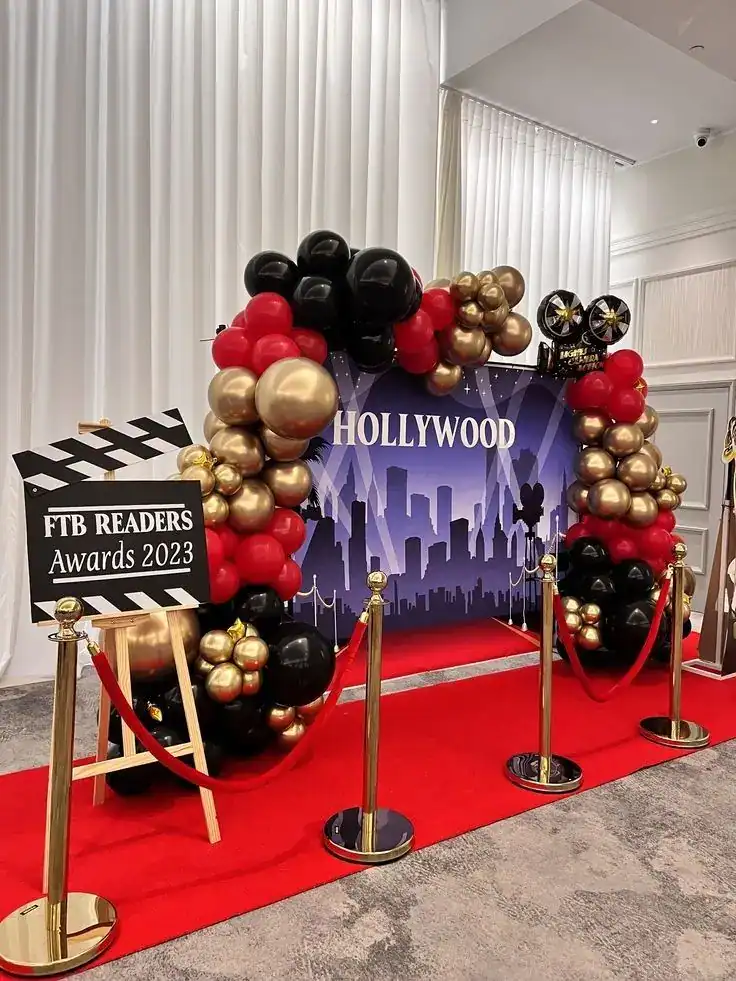Hollywood red carpet photo booth setup with balloon arch and star decorations for an end-of-year school party