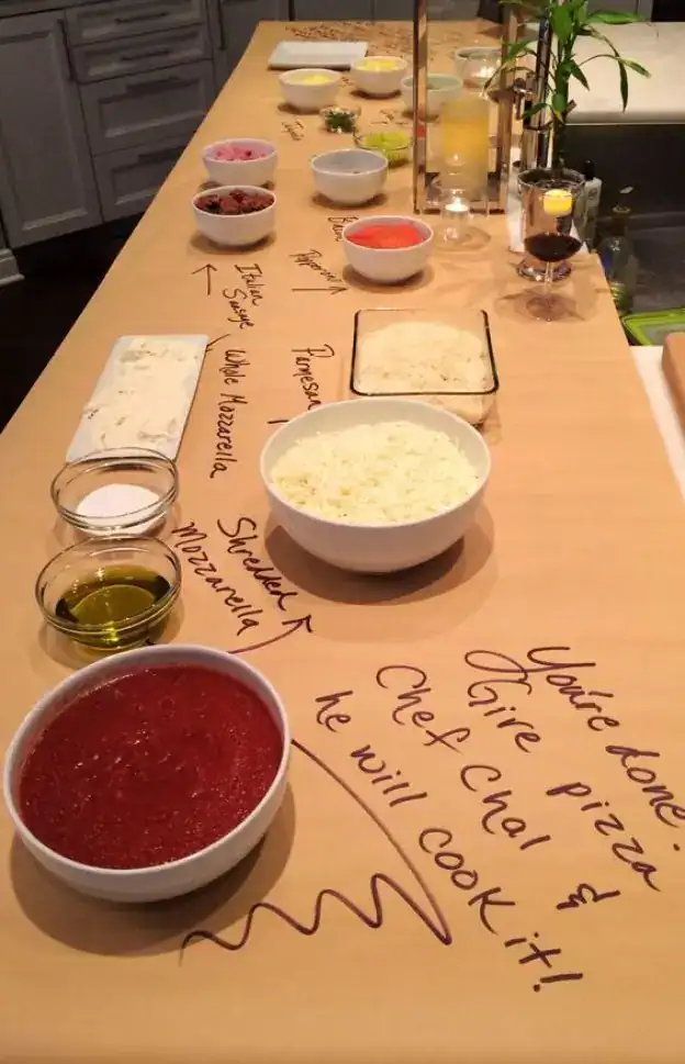 Students building their own mini pizzas at a DIY pizza station during an end-of-year school party