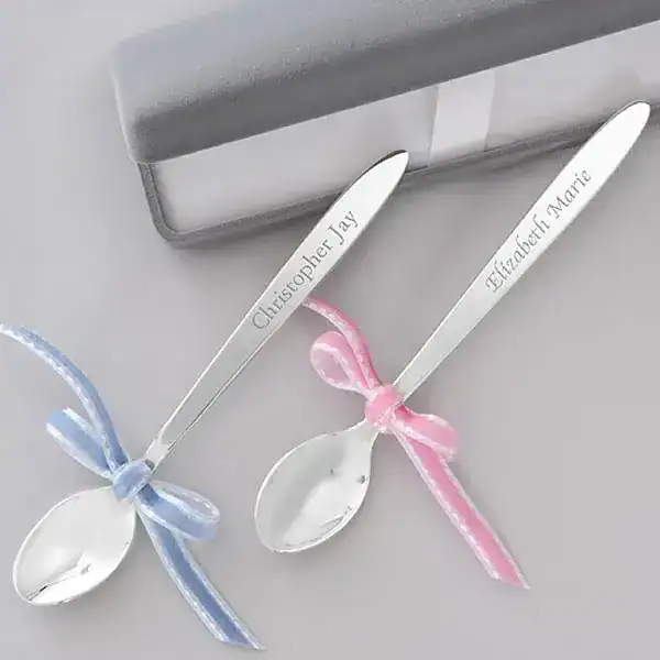 Personalized first tooth celebration spoons with blue and pink ribbons.