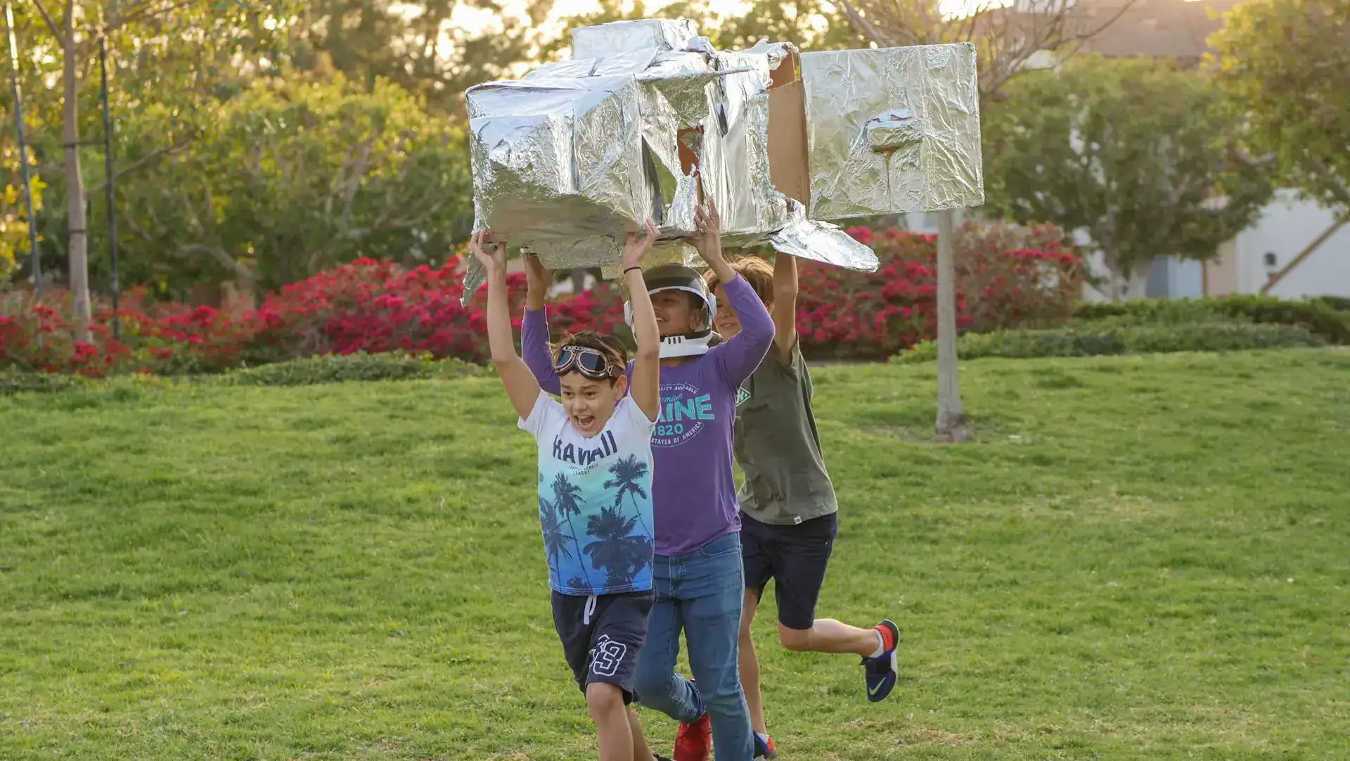 Kids playing with homemade cardboard rocket at a backyard party.
