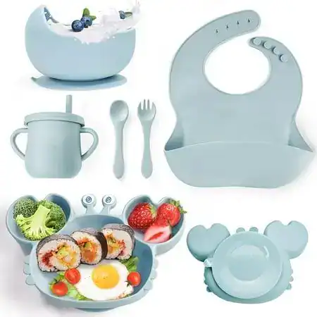 Baby feeding set with bib, food plate, spoon, fork, and sippy cup for first tooth celebration.