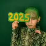 27 New Year's Eve Activities for Kids Child holding "2025" sign for New Year's Eve party with vibrant green background.