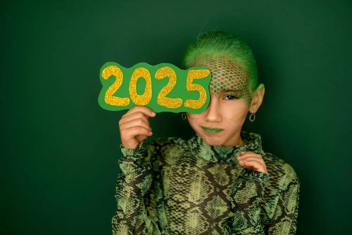 Child holding "2025" sign for New Year's Eve party with vibrant green background.