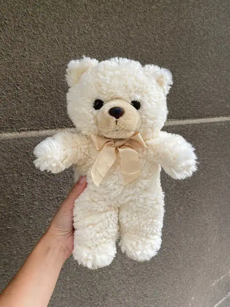 Adorable white teddy bear with a beige ribbon, perfect for first tooth party gift ideas.