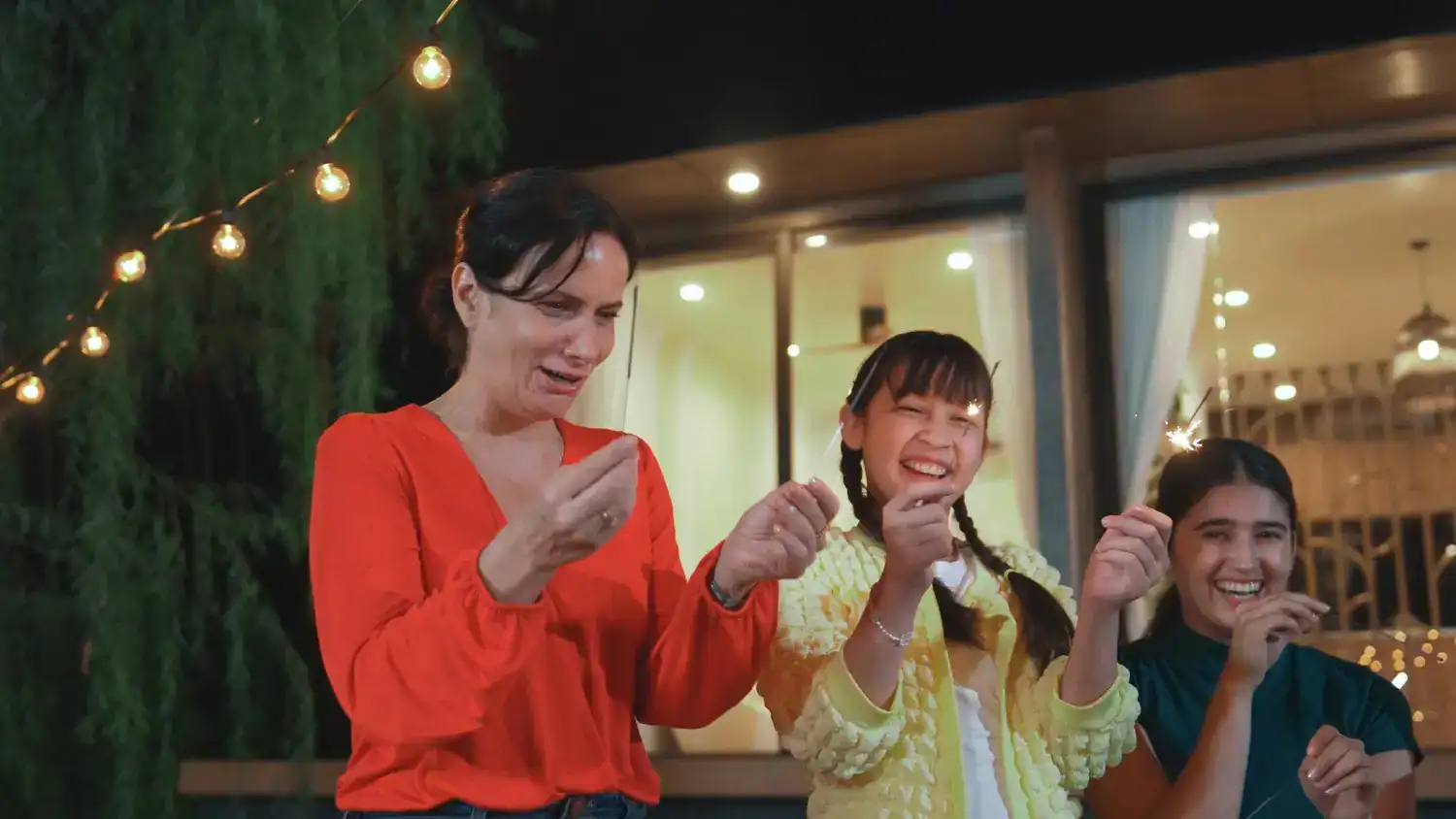 Group of women celebrating New Year’s Eve with drinks and laughter indoors.