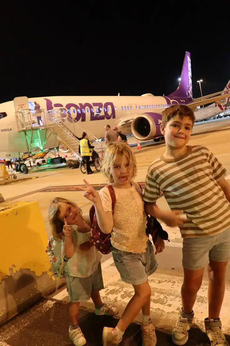 Children at night near airplane on tarmac.