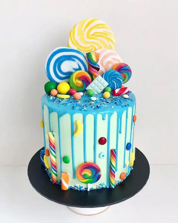 Drip cake with dark chocolate ganache dripping down the sides, topped with sprinkles and candy decorations