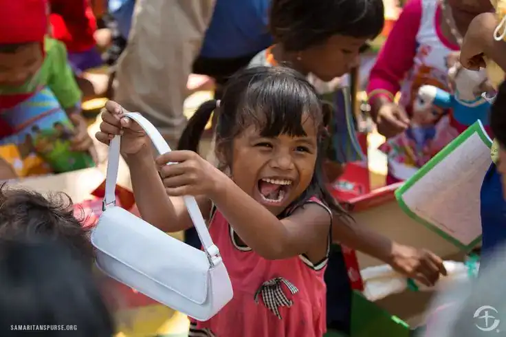 Child girl smiling with gift bag at birthday party.