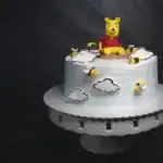 33 Unique Birthday Cake Ideas Winnie the Pooh themed birthday cake with clouds and bees for kids' celebration.