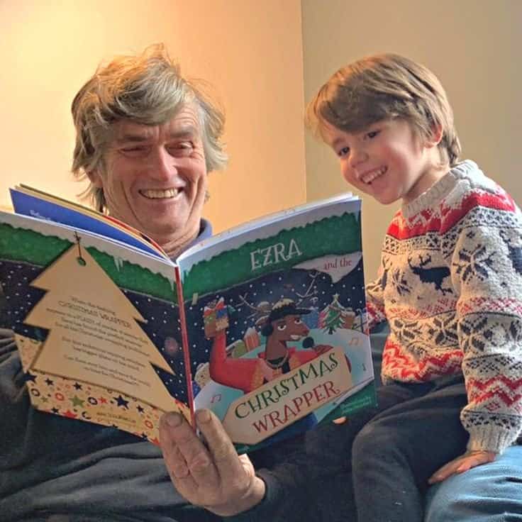 Grandpa and grandson reading a Christmas gift book together, celebrating holiday joy.