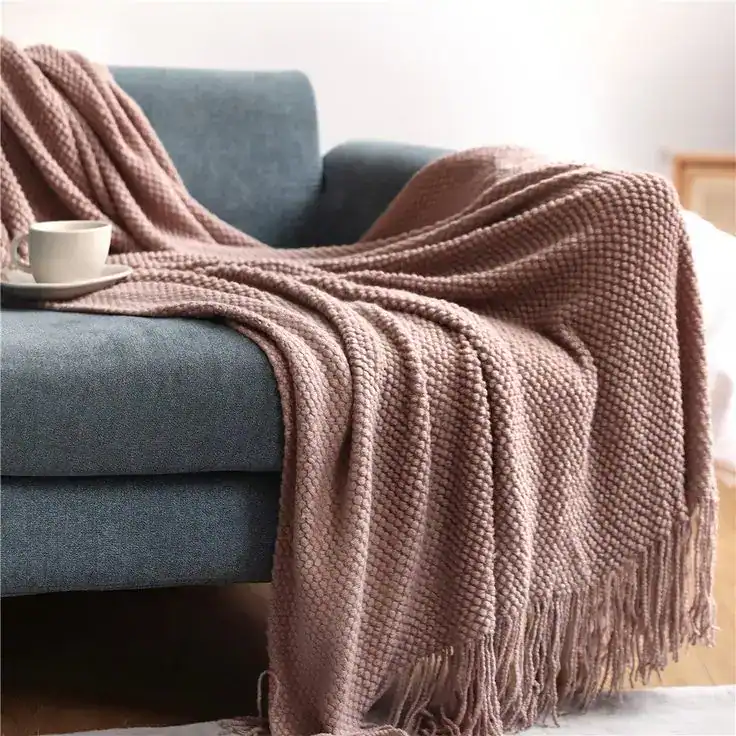 Soft pink textured throw blanket draped over a modern blue sofa.