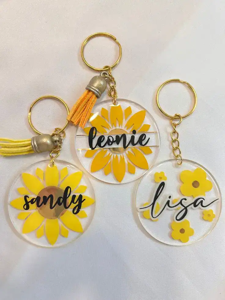 Personalized yellow flower keychains with custom names for housewarming party favors.
