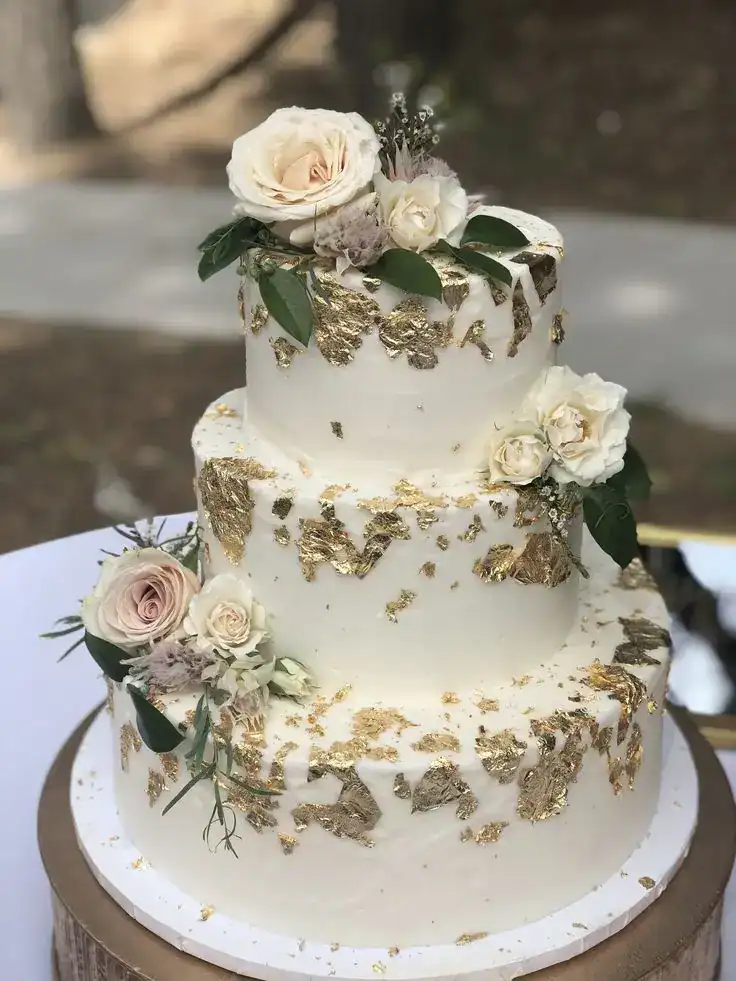Elegant birthday cake with edible gold leaf panels on white fondant for a luxurious milestone celebration