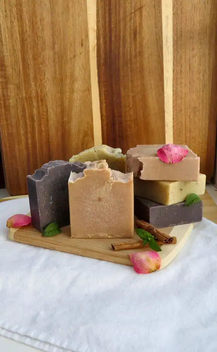 Colorful natural soap bars displayed on a wooden board for party favors.