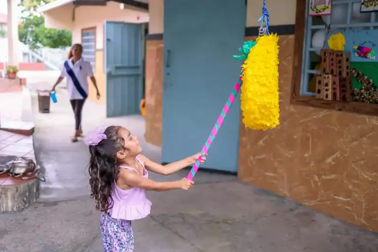 Girl pulling a piñata during birthday celebration outside.