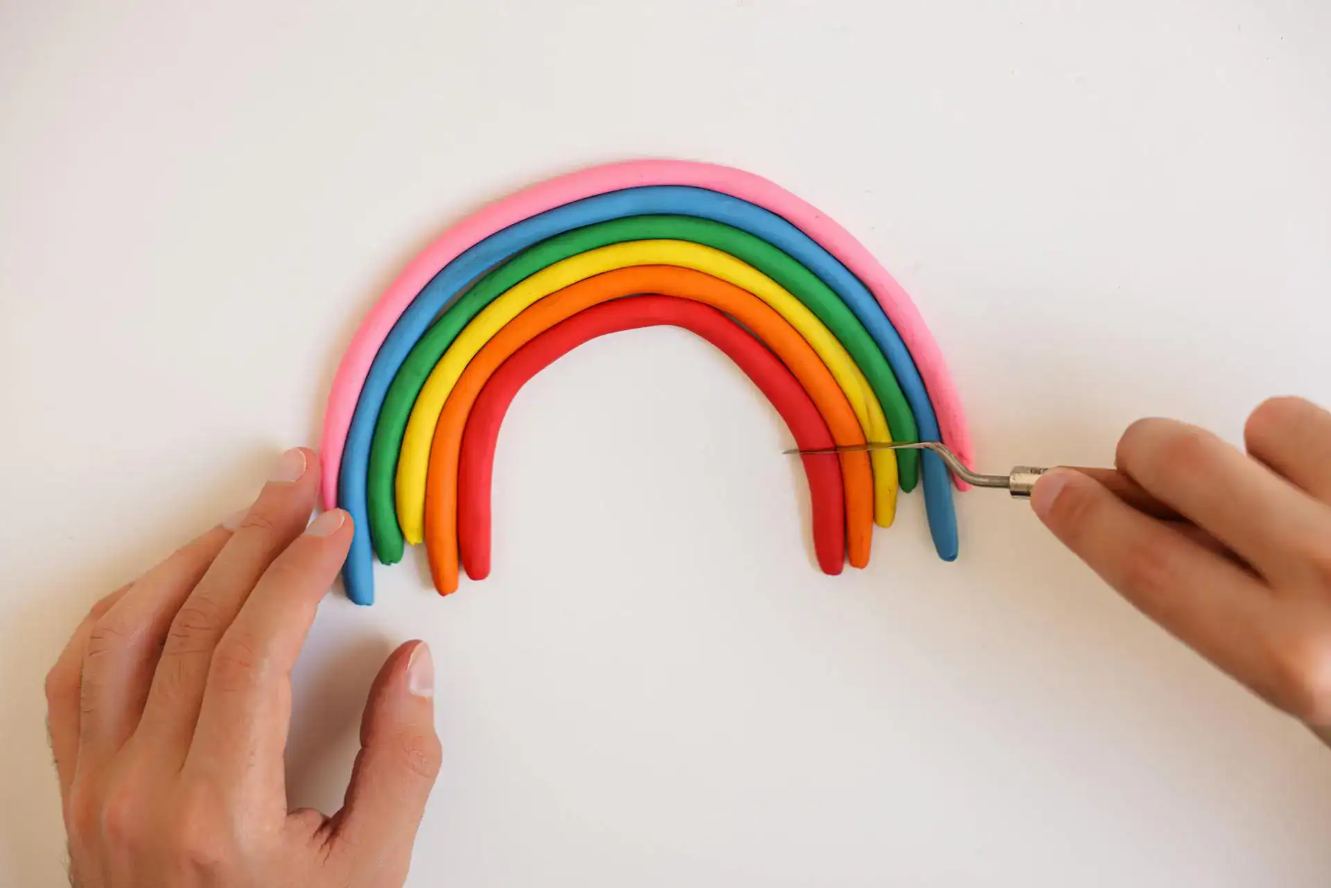 Rainbow craft with colorful clay and a small tool for kids' activities.