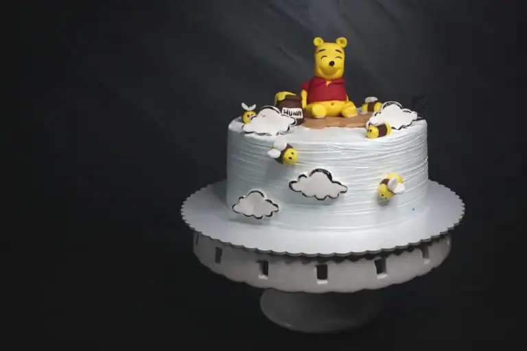 Winnie the Pooh themed birthday cake with clouds and bees for kids' celebration.