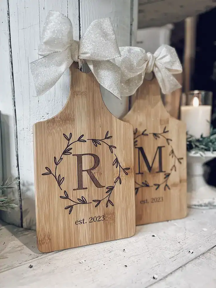Personalized wooden monogram cutting boards with initials and bows for housewarming gifts.