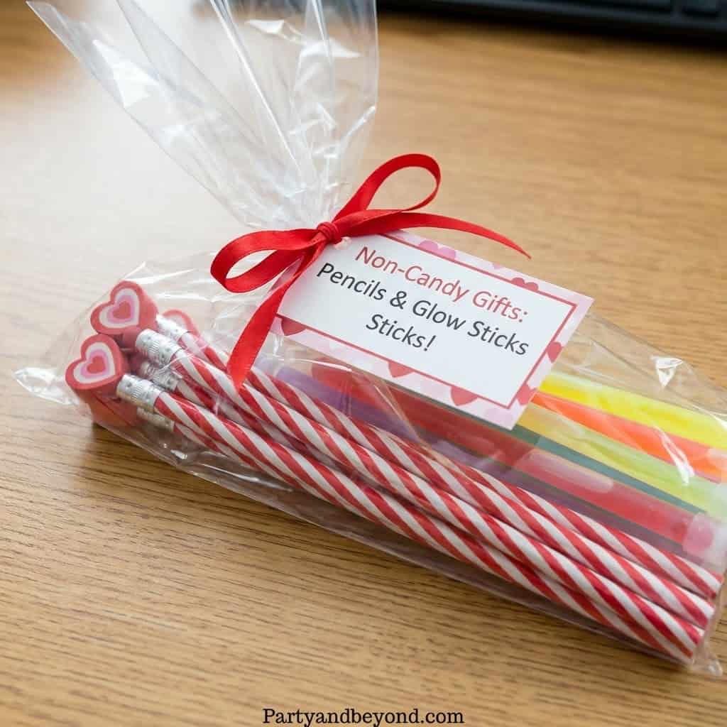 Non-candy Valentine gifts for kids including pencils and glow sticks in a clear bag.