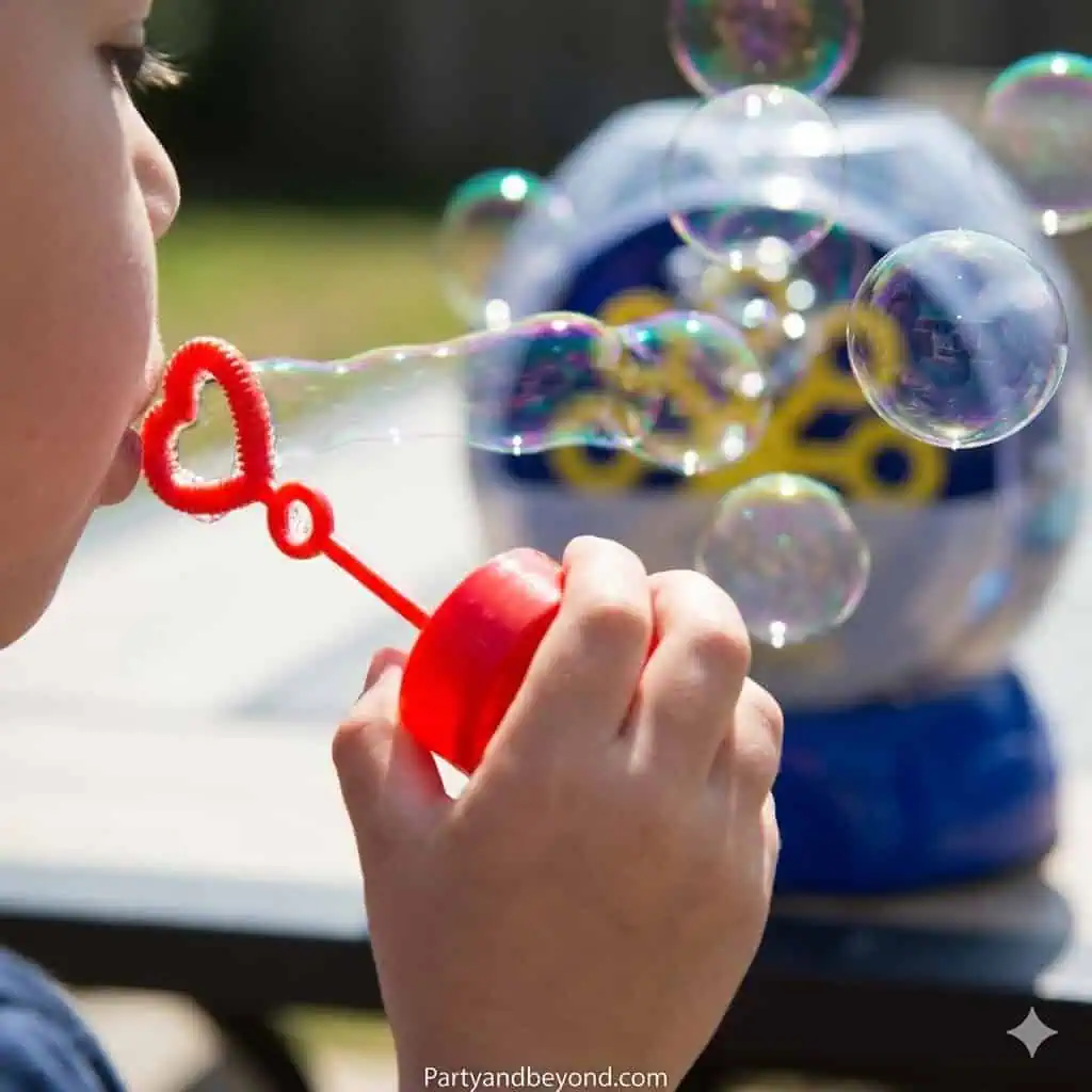 Child blowing bubbles with a bubble machine in the background.