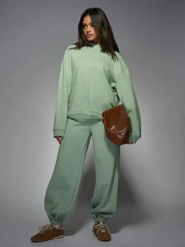 Woman in mint green loungewear with brown bag for St. Patrick's Day.