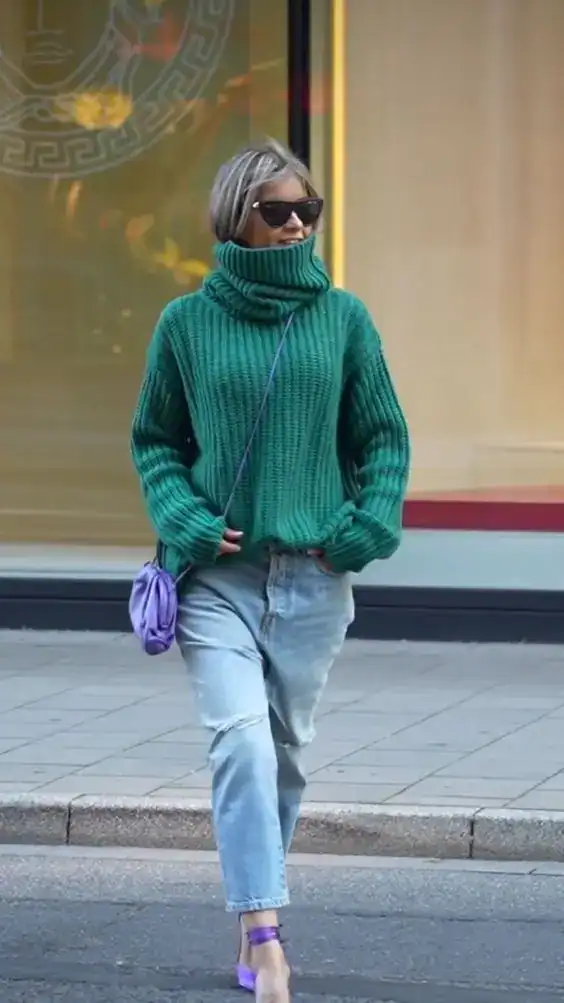 Woman in green turtleneck sweater and jeans celebrating St. Patrick's Day.