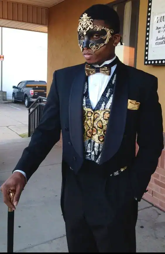 Elegant Mardi Gras man in a black tuxedo with gold and black mask, ornate accessories, and bow tie f.