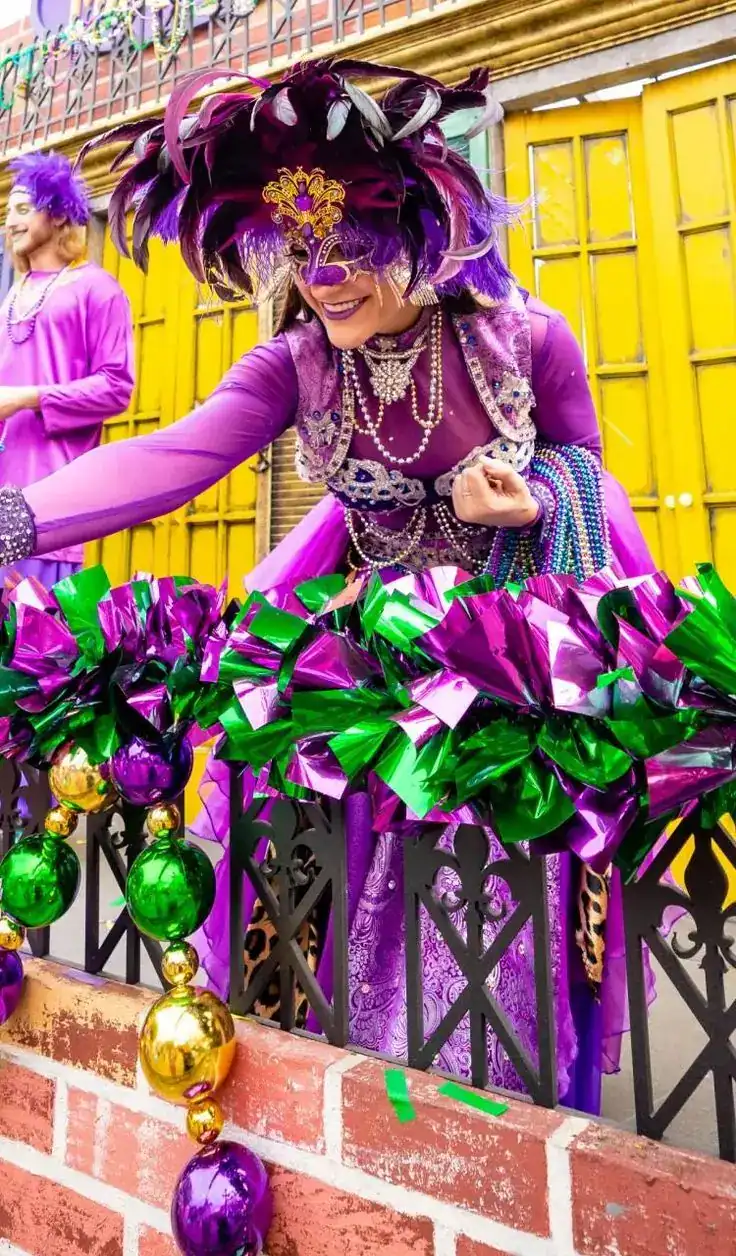 Colorful Mardi Gras parade costume with vibrant purple, gold, and green feathers and beads.