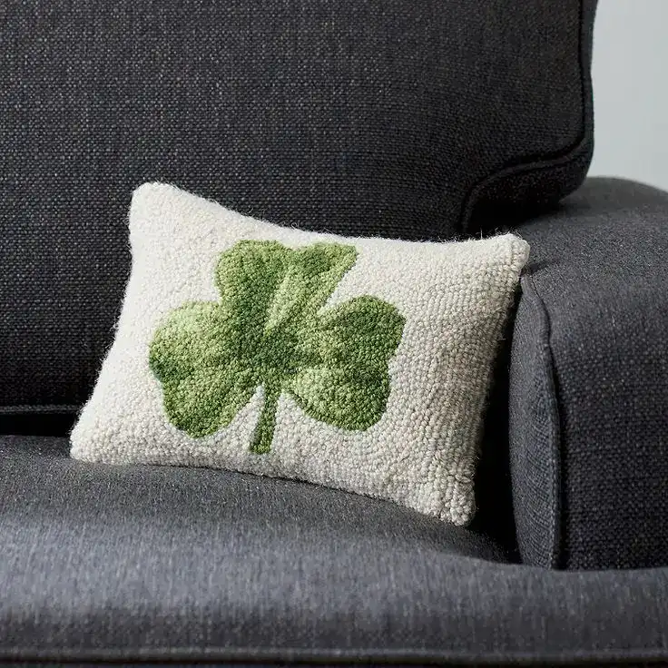 Decorative pillow with a green shamrock for St. Patrick's Day celebrations.