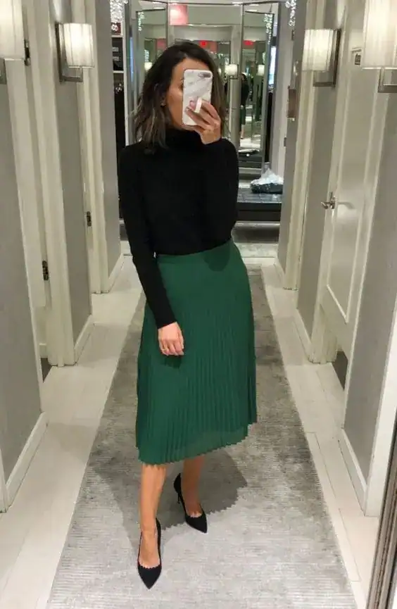 Woman in green pleated skirt and black top for St. Patrick's Day celebration.