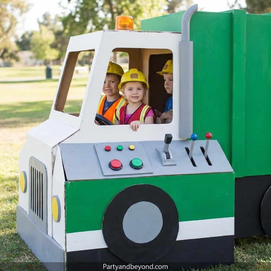 Construction truck themed birthday party photo with children in safety helmets.