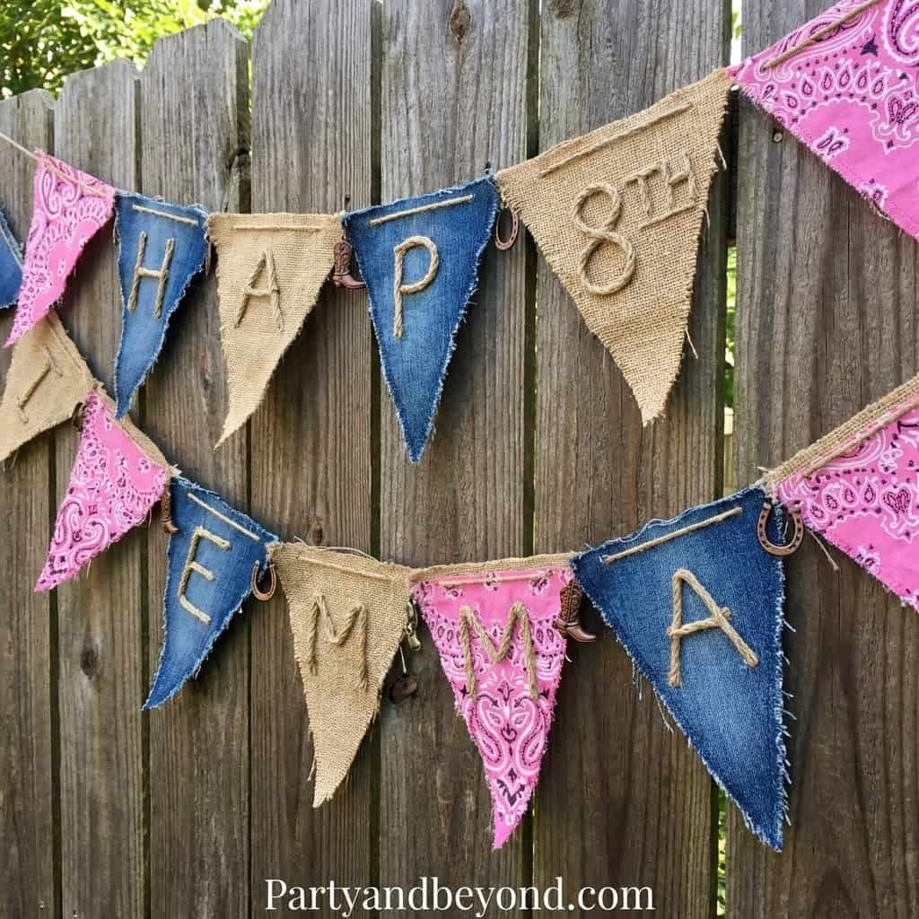 Colorful cowgirl-themed birthday banner with "Happy 8th" and "Yay" flags on a wooden fence.