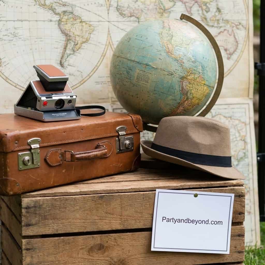 Travel-themed party decor featuring a vintage suitcase, globe, and hat for a Finding Nemo birthday c.