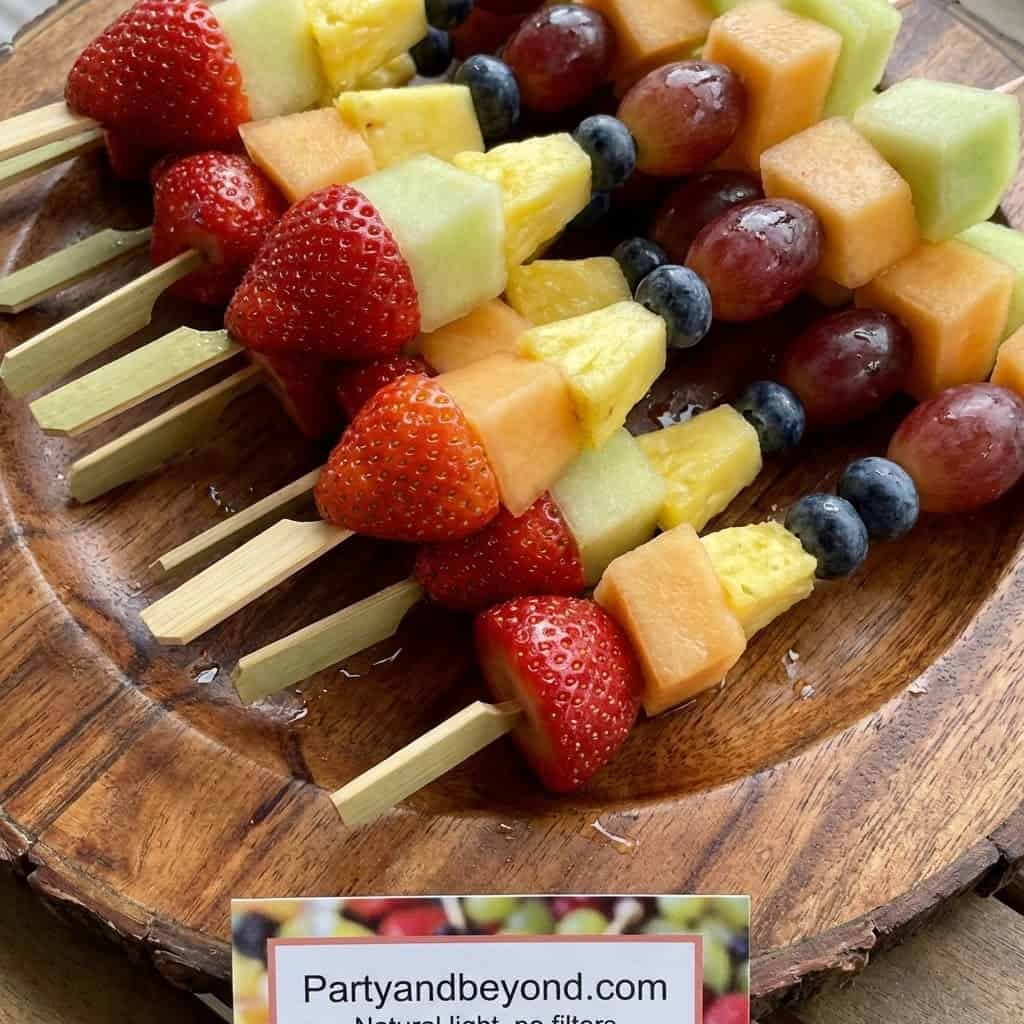 Colorful fruit skewers with strawberries, melons, grapes, and pineapple for party snacks.