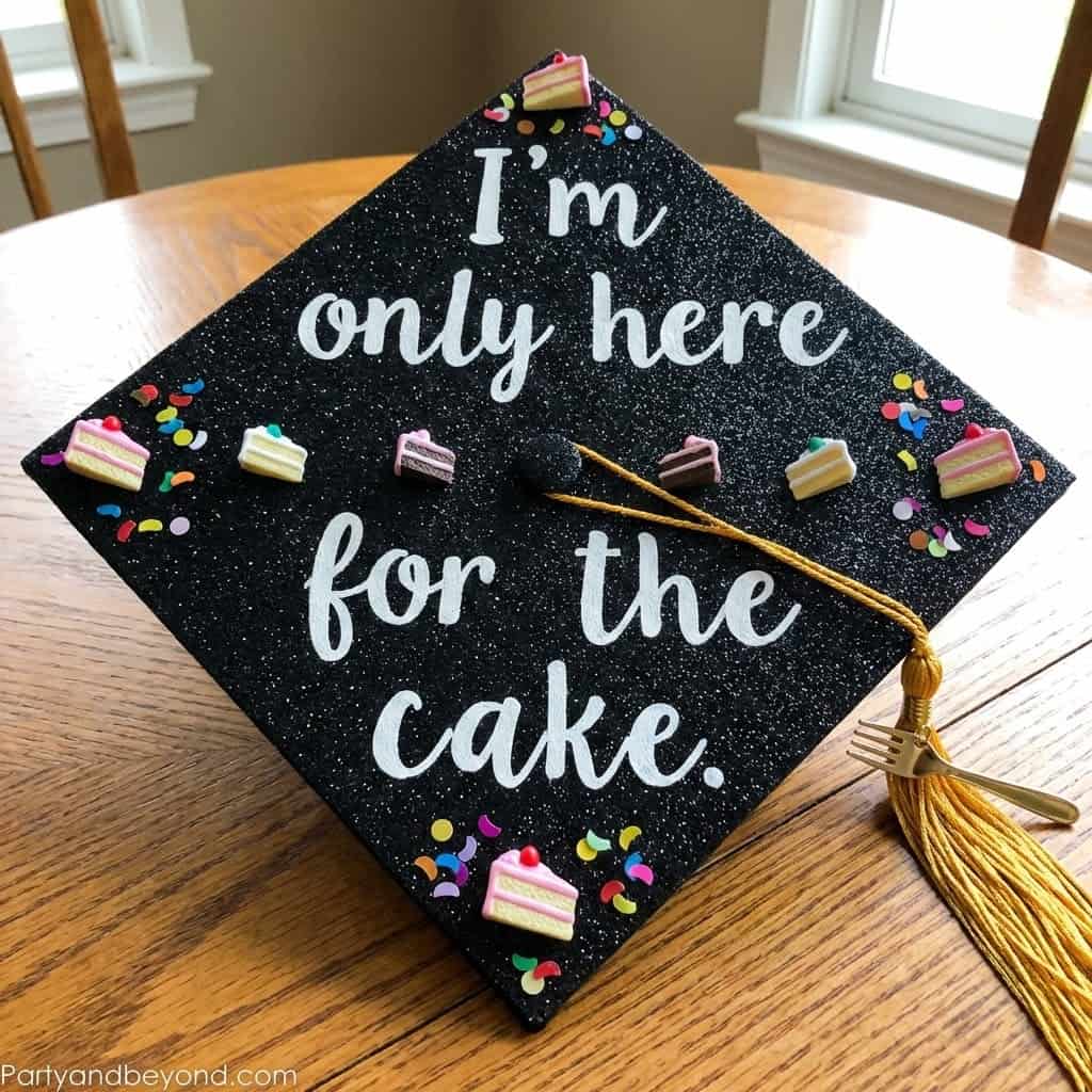 Graduation cap with cake-themed decorations and humorous message for graduation party.