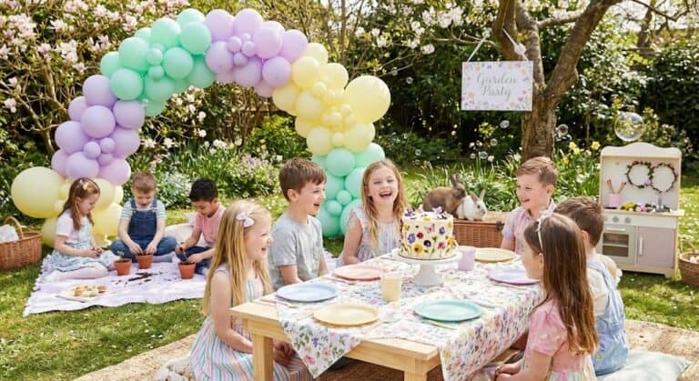 Kids enjoying a spring birthday party outdoors with colorful balloon arch and festive decorations.