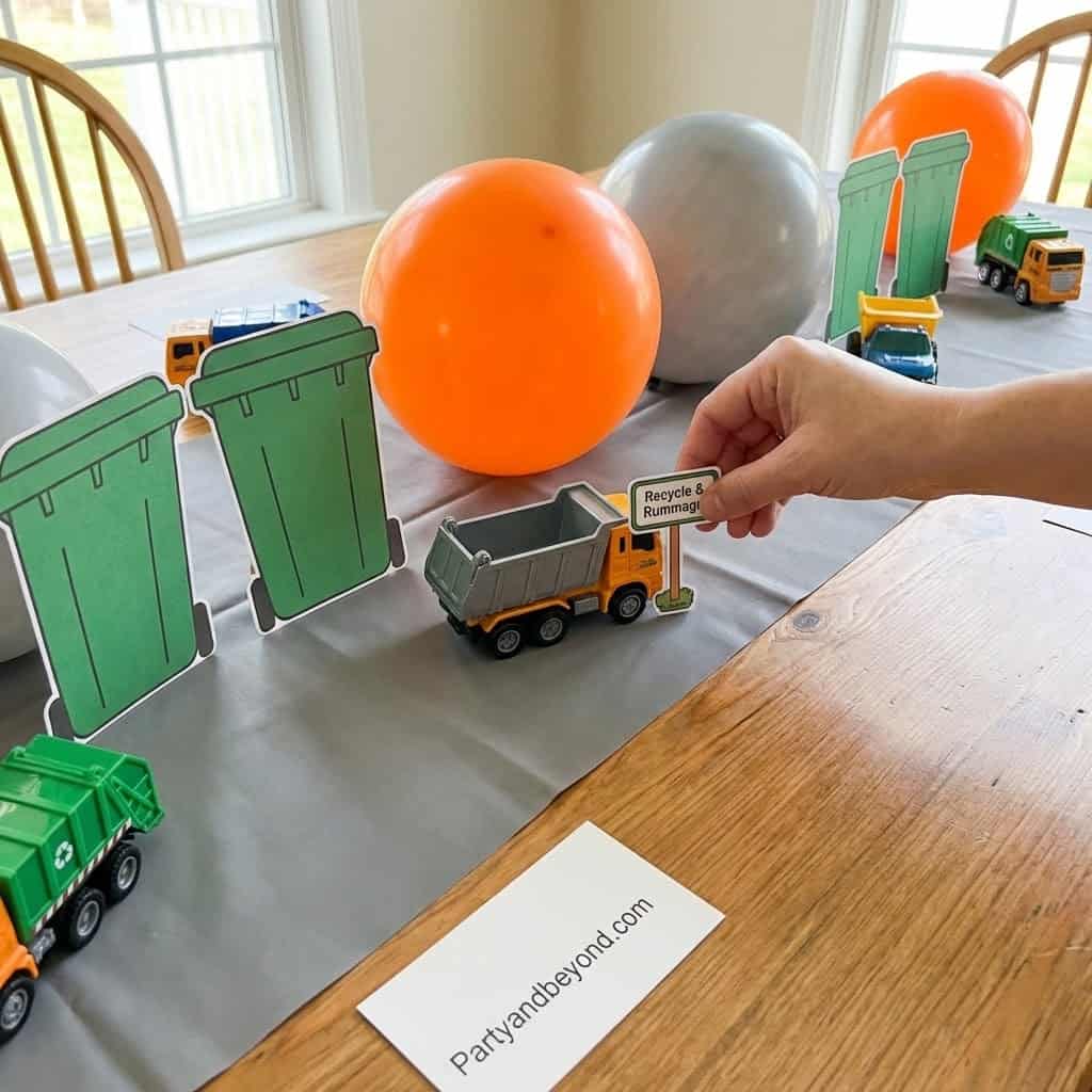 Trash truck toy with recycling bins and balloons at a birthday party.