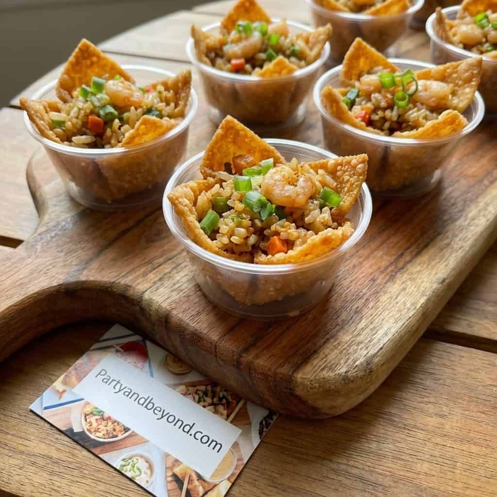 Delicious party food served in small cups with rice, vegetables, and crispy chips.