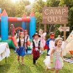 15 Backyard Kids Party Themes for Fun and Memorable Celebrations Kids enjoying a themed outdoor birthday party with a bounce house and camping setup.