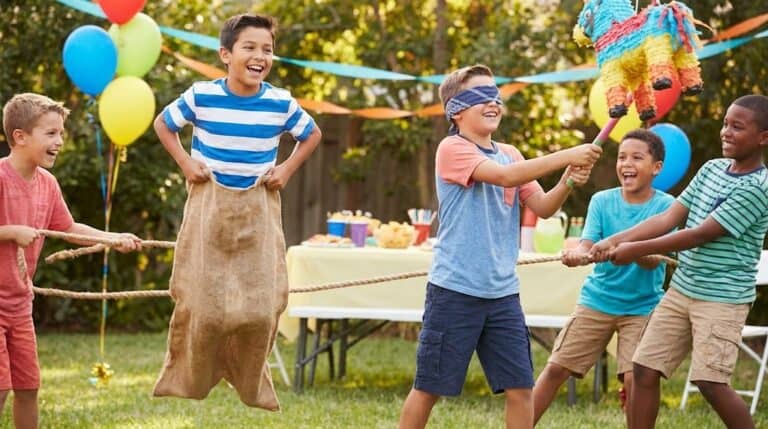 Kids playing tug-of-war at a birthday party with balloons and decorations.
