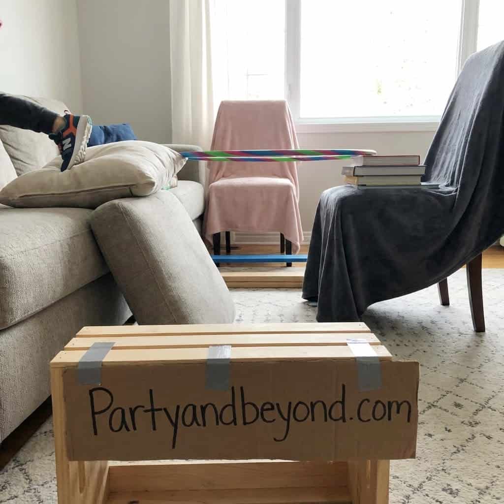Indoor kids' birthday party game setup with a hula hoop and a cardboard sign.