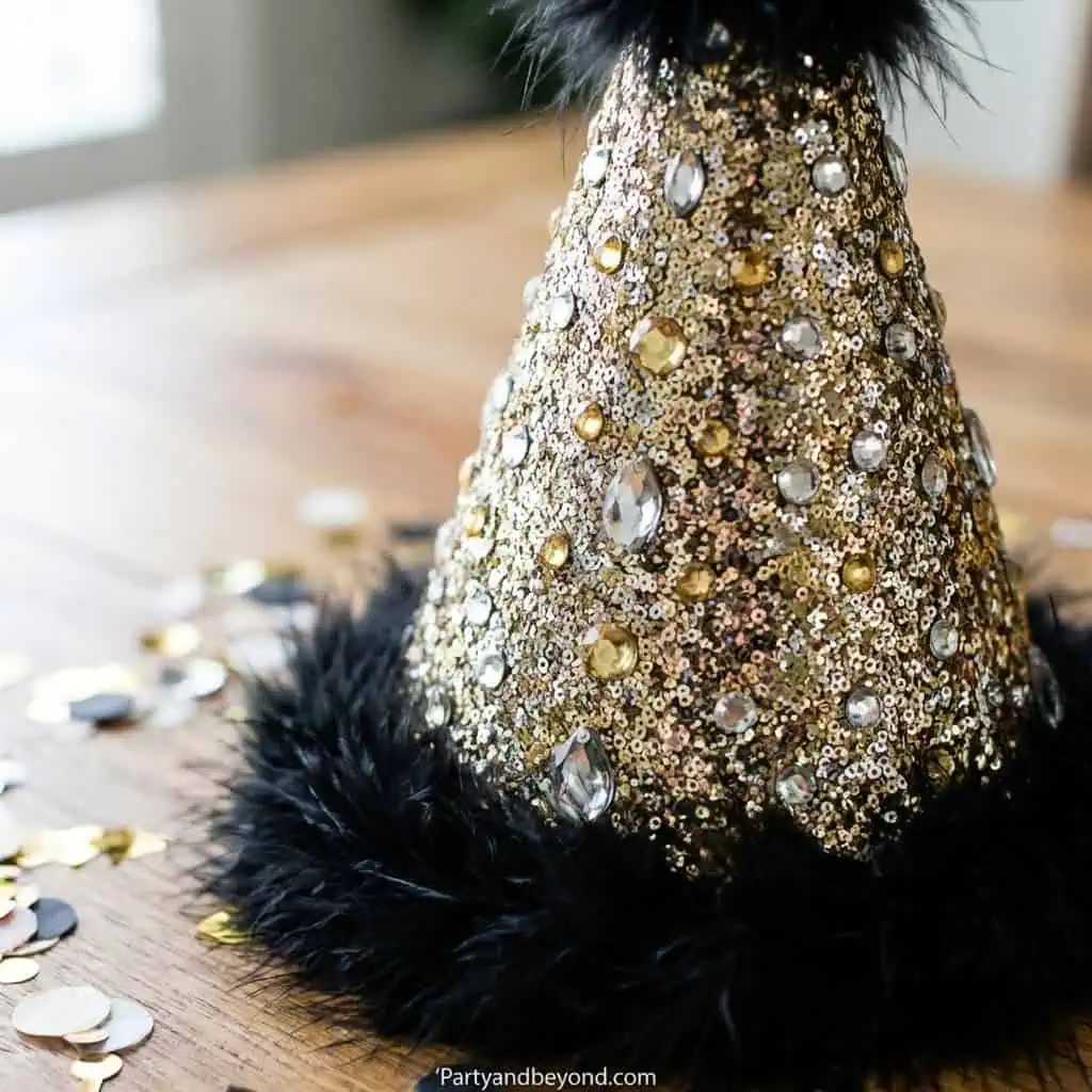 Gold and black graduation cap decoration with sequins and feathers.