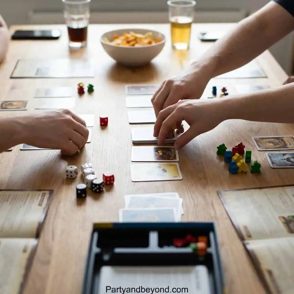 People playing a card game at a graduation celebration with snacks and drinks.