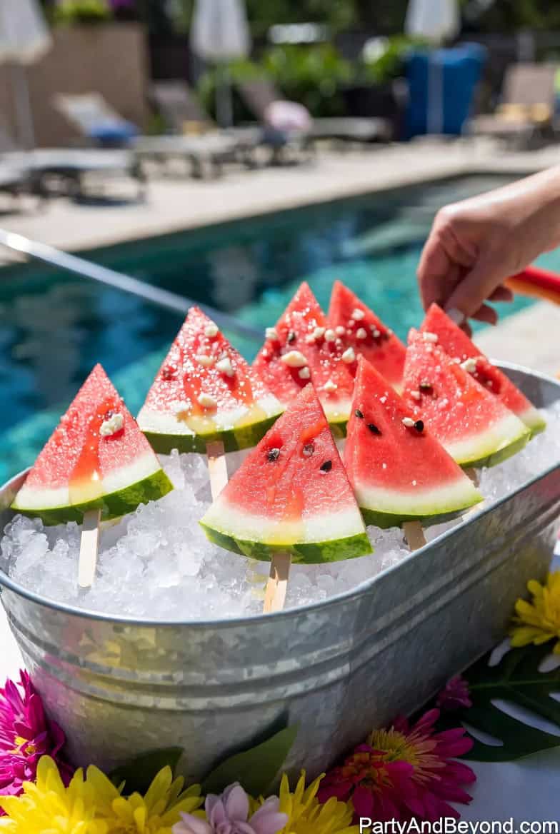 Watermelon popsicles on ice at a summer pool party, perfect for refreshing guests.