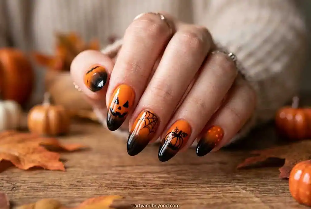 Orange to black ombré Halloween nails with glowing pumpkin accent art.