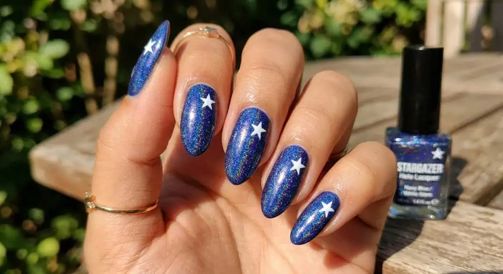 : Shiny holographic blue nails with white star accents for a sparkling patriotic look.