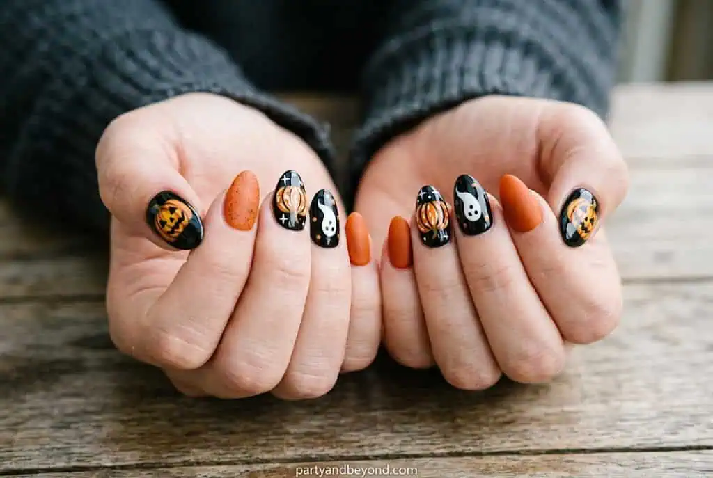 Matte black and glossy orange Halloween nails with pumpkin accent.